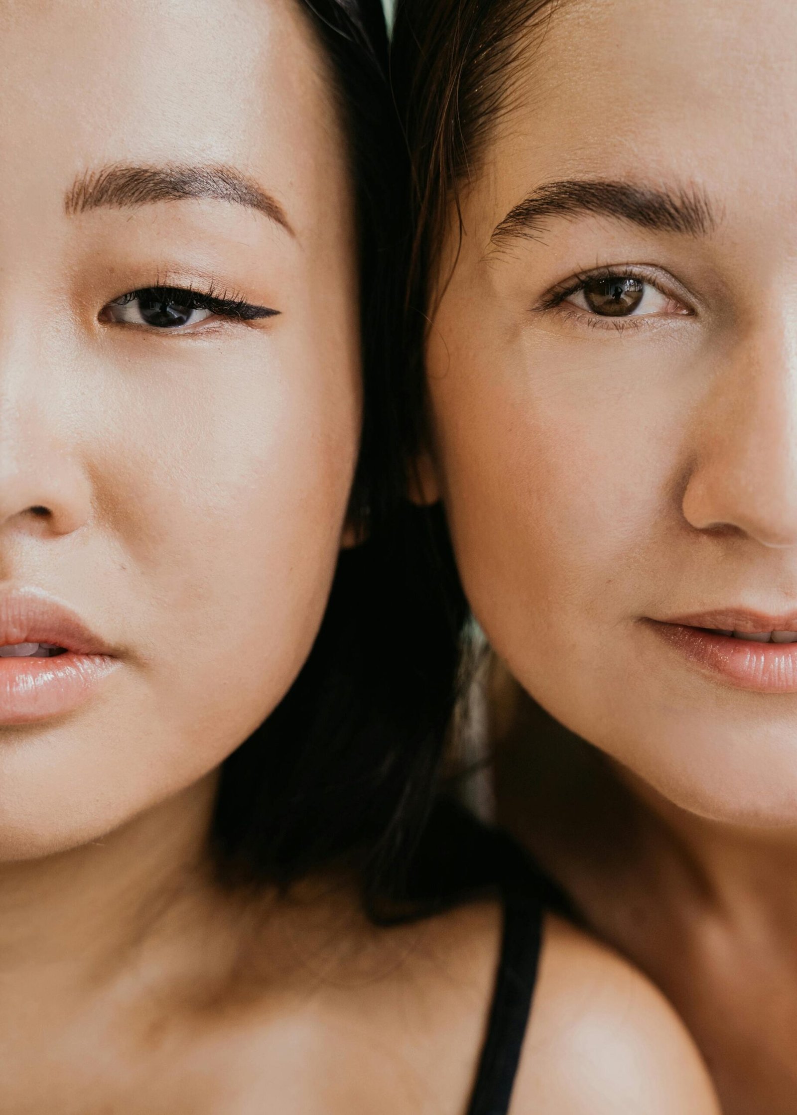 Close-up portrait of two people's faces side by side, showing expressions and details of eyes and skin tones, against a neutral background.